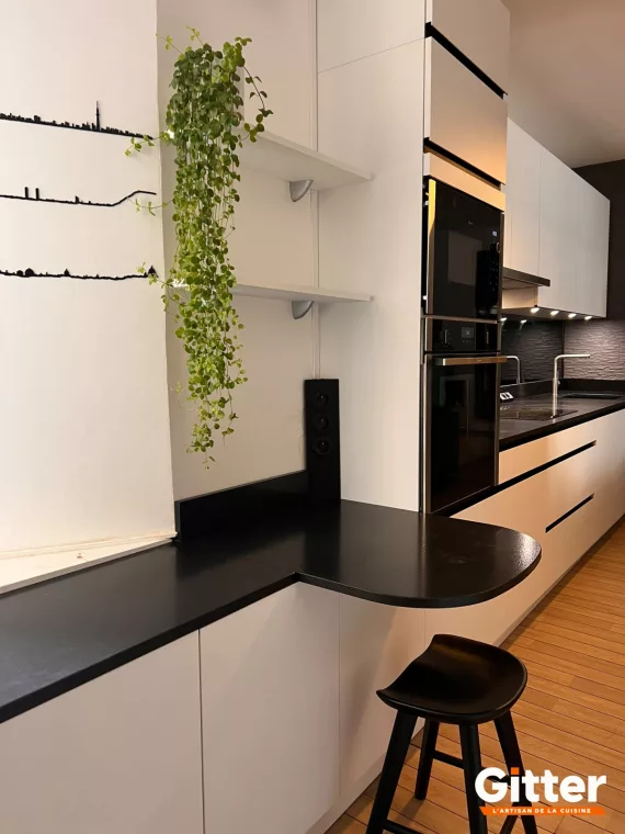 Cuisine blanche avec retour snack noir, colonnes four et étagères ouvertes, réalisation Gitter à Hagondange