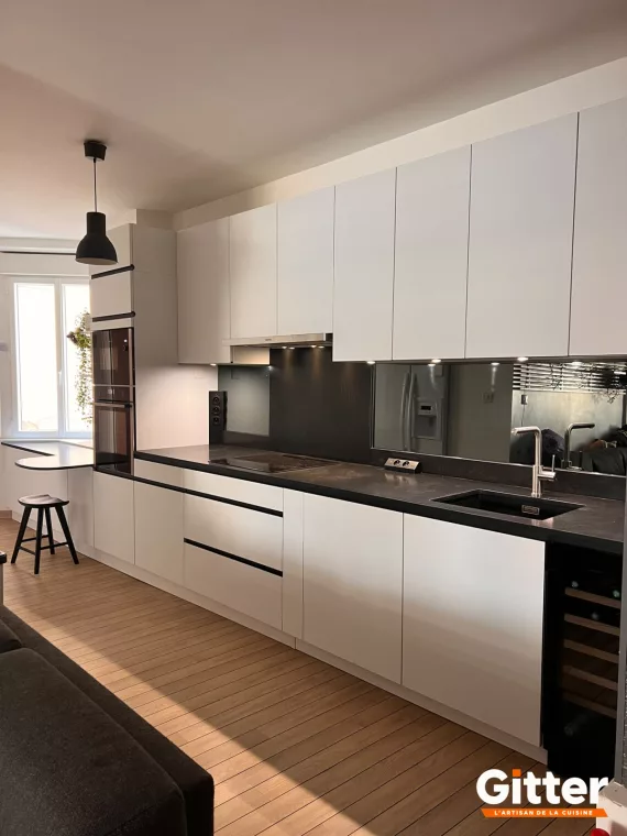 Long linéaire blanc sans poignées, plan de travail noir et crédence effet miroir fumé, réalisation Gitter à Hagondange