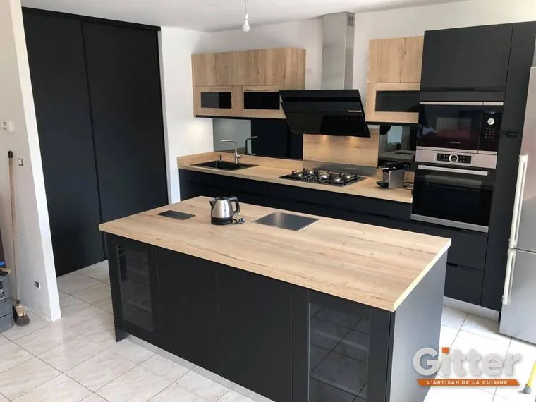Cuisine avec îlot central, façades noires mates et bois, plan de travail bois sur l'îlot, réalisation Gitter à Marly