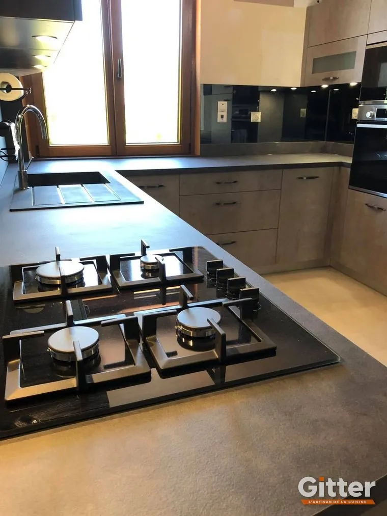 Cuisine en U, plan de travail foncé, crédence noire brillante et plaque gaz cinq feux, réalisation Gitter à Talange