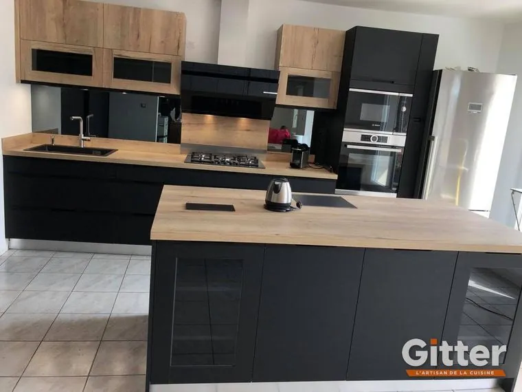 Cuisine : grand îlot central, façades anthracite mates et plan de travail bois, réalisation Gitter à Mondelange