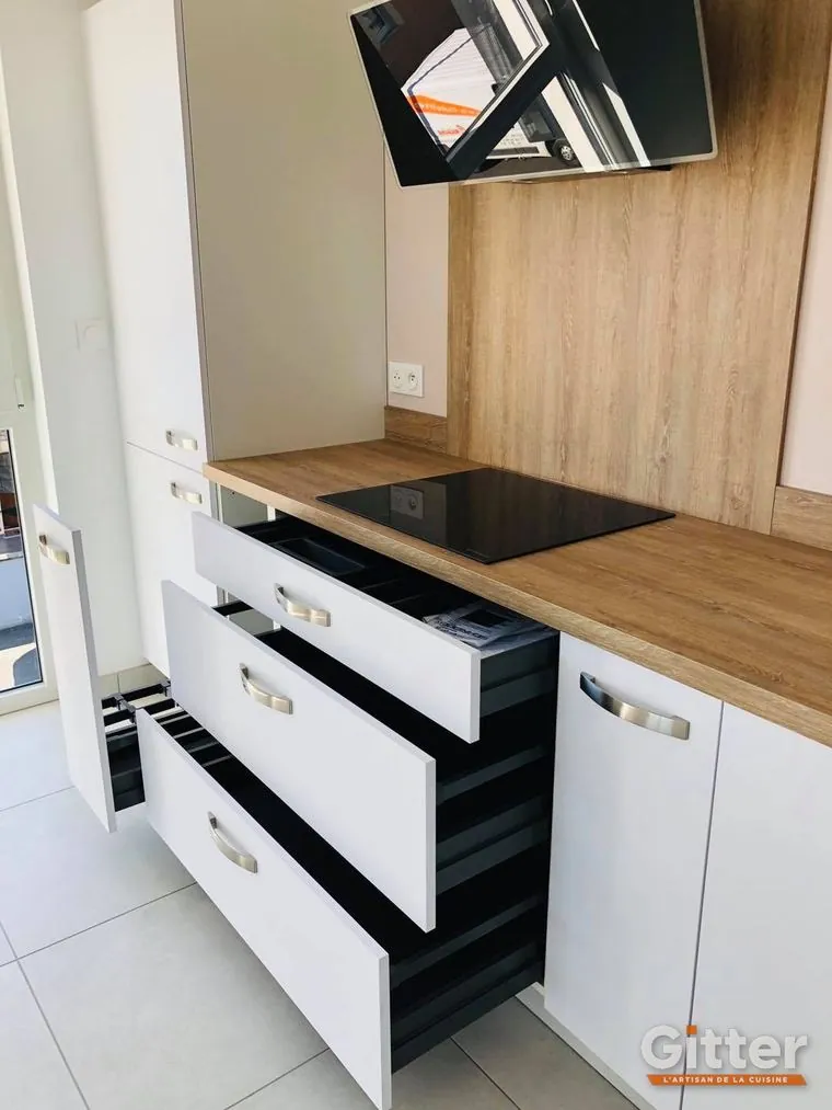 Cuisine : façades blanches sans poignées, tiroirs à l'anglaise, plan de travail et crédence bois, réalisation Gitter à Guénange