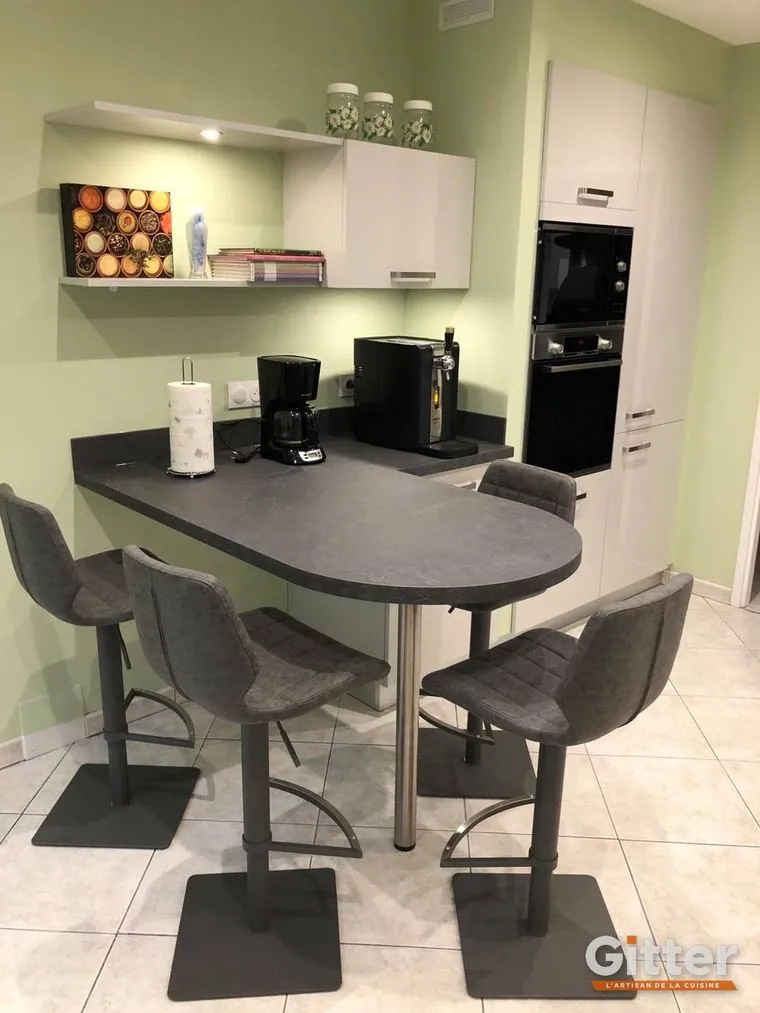 Cuisine : coin repas ovale, façades blanches et colonnes four sur mur vert, réalisation Gitter à Terville