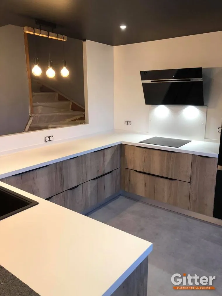 Cuisine en U, façades bois, plan de travail blanc et hotte noire inclinée, réalisation Gitter à Amnéville