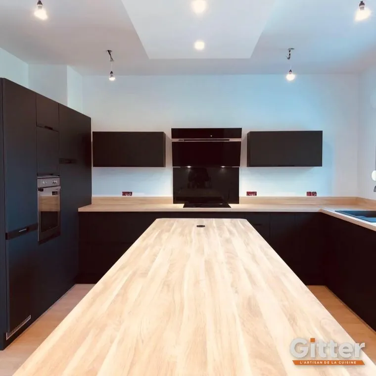 Cuisine en U, façades sombres, plan de travail bois clair et éclairage sous meubles, réalisation Gitter à Trémery
