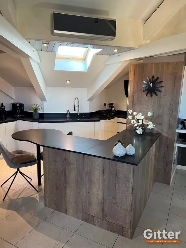 Cuisine sous pente avec péninsule bois arrondie et plan de travail noir, réalisation Gitter à Villers-lès-Nancy