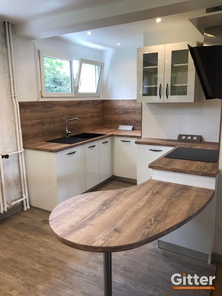 Cuisine : coin repas ovale en bois, façades blanches et crédence bois, réalisation Gitter à Amnéville
