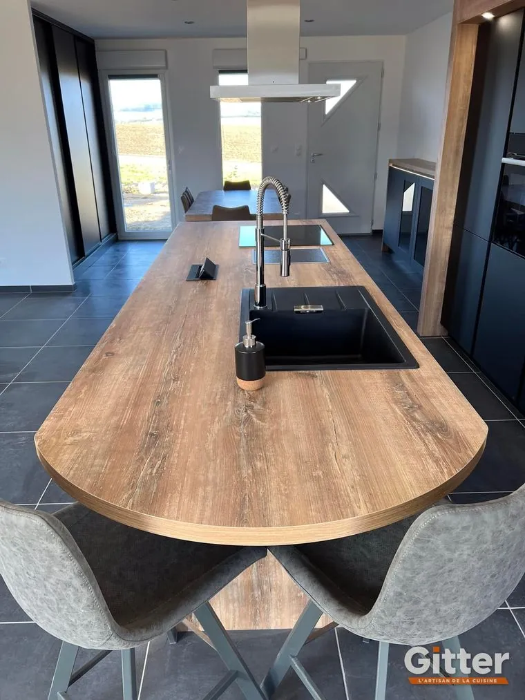 Cuisine : plan de travail bois arrondi formant table, façades noires et évier noir, réalisation Gitter à Serémange-Erzange