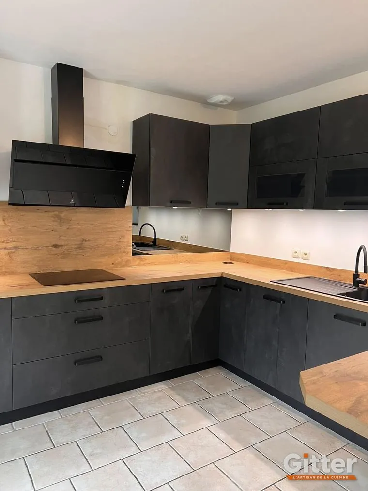 Cuisine en L, façades effet béton foncé, plan de travail bois et hotte cheminée noire, réalisation Gitter à Yutz