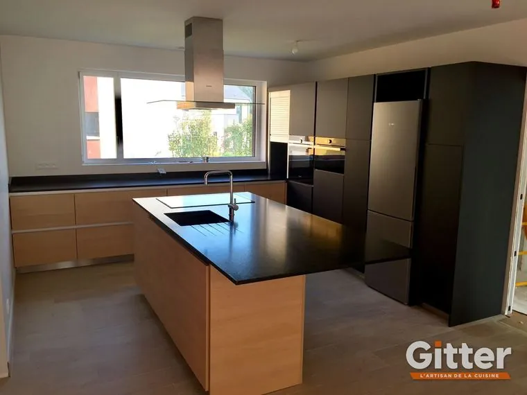Îlot bois à plan de travail noir, façades sombres et hotte inox, réalisation Gitter à Yutz