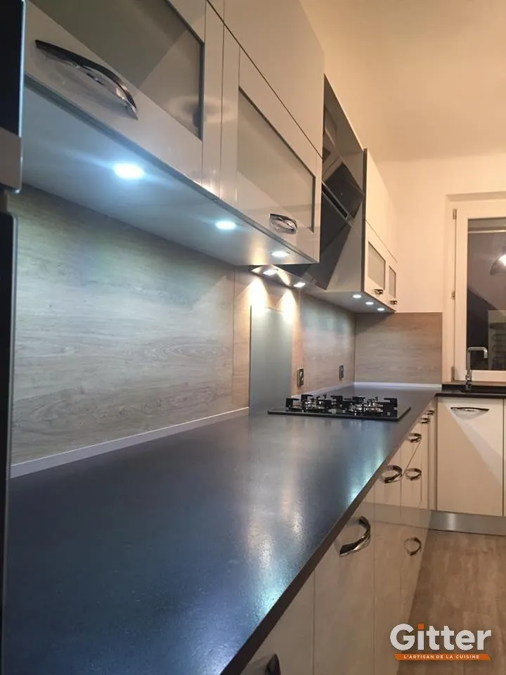 Cuisine : façades claires, plan de travail foncé, crédence effet pierre et plaque gaz, réalisation Gitter à Kanfen