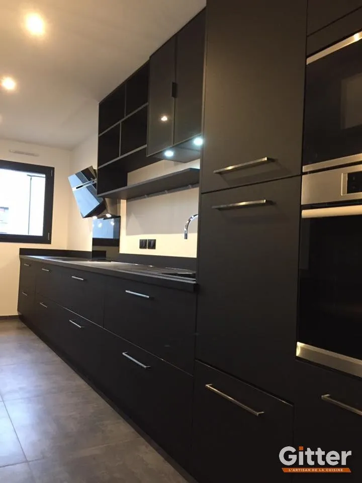 Cuisine : façades anthracite brillantes, colonnes four et plan de travail foncé, réalisation Gitter à Rombas