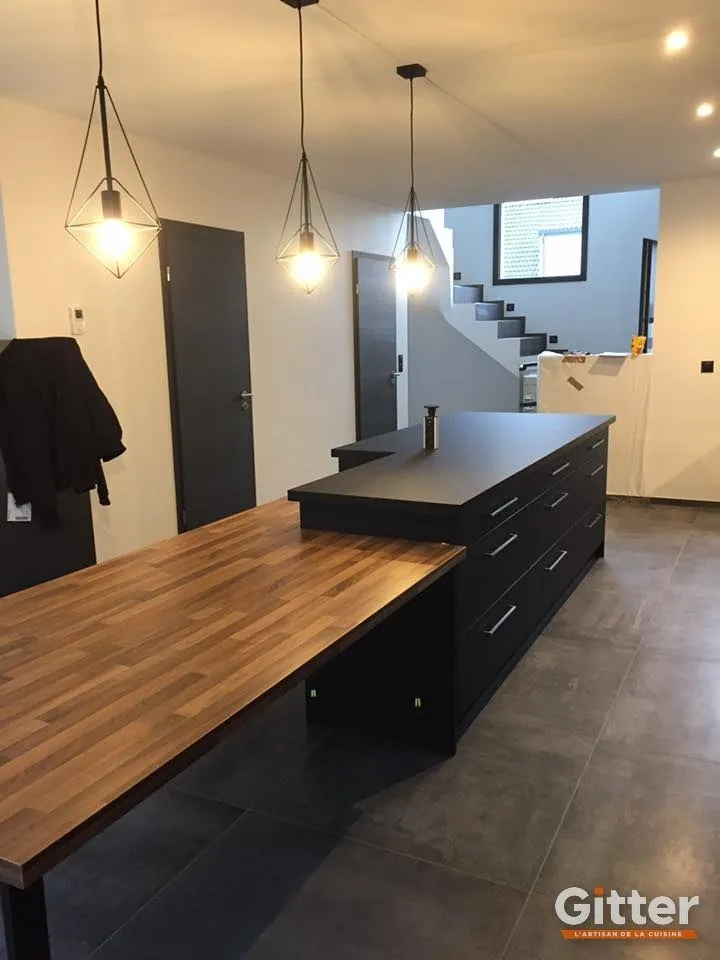 Îlot noir prolongé d'une table bois, ouvert sur l'escalier, réalisation Gitter à Laxou