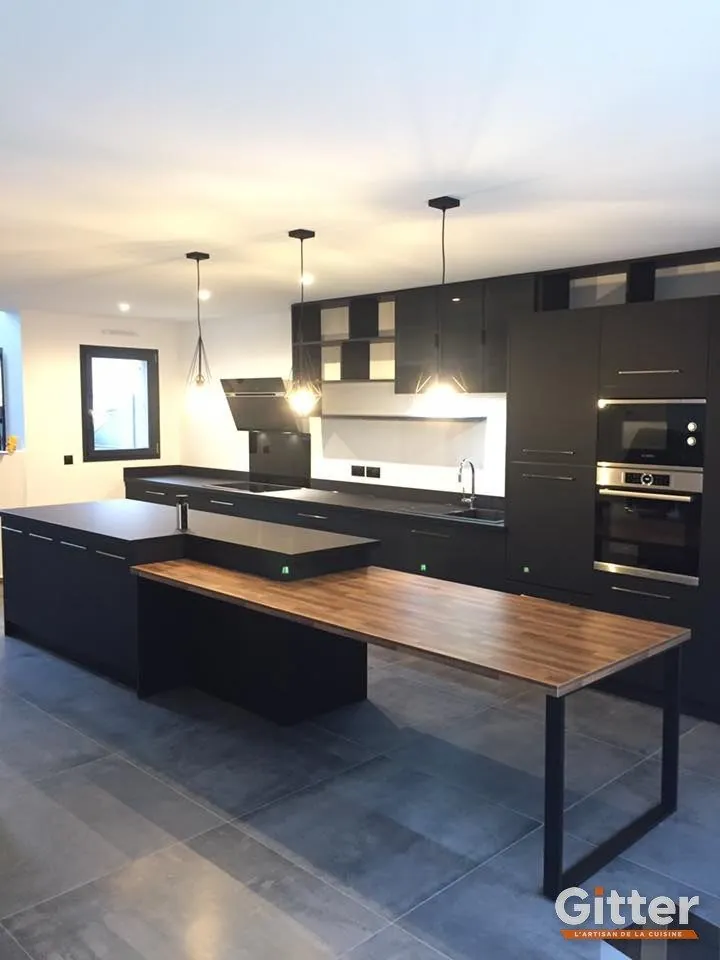 Îlot noir prolongé d'une table bois, façades sombres et suspensions, réalisation Gitter à Ennery