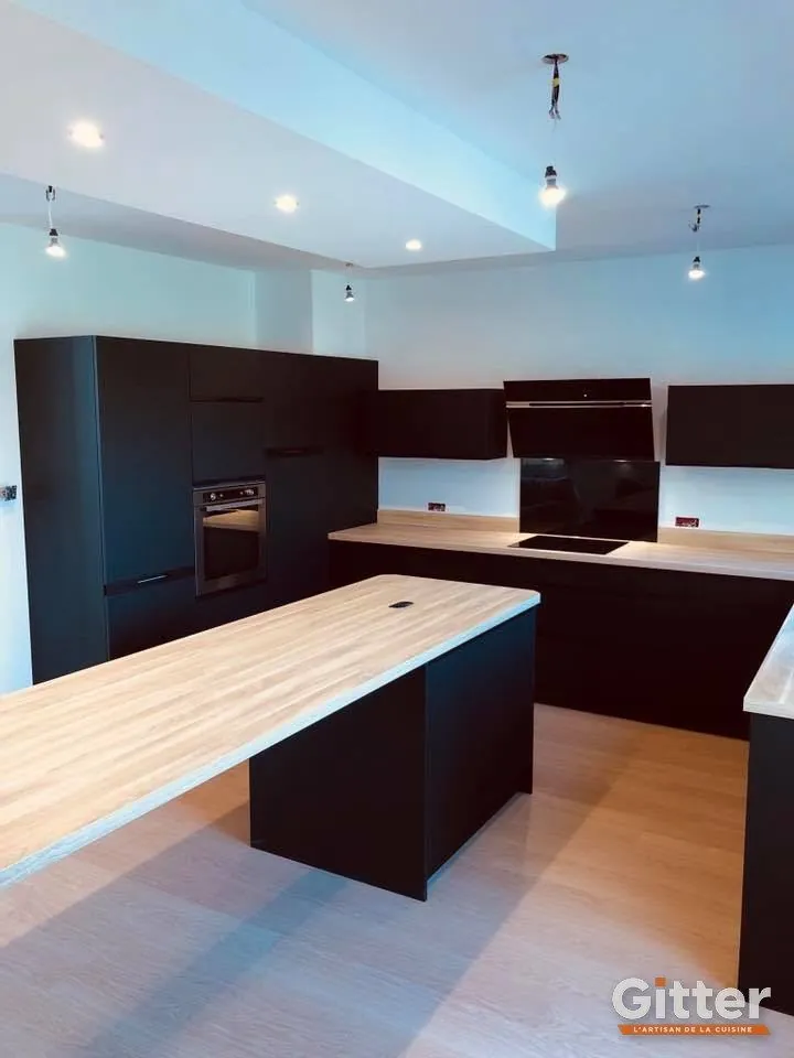 Cuisine : grand îlot noir à plan de travail en bois, colonnes noires, réalisation Gitter à Florange
